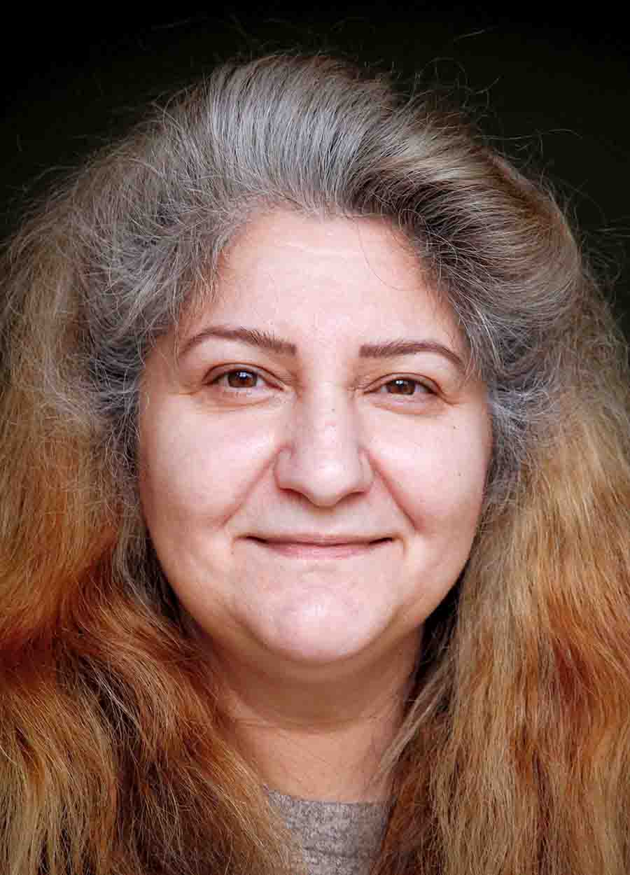 Porträt einer Frau mit langen, graubraunen Haaren und einem sanften Lächeln. Sie blickt direkt in die Kamera und trägt einen dezenten Pullover.